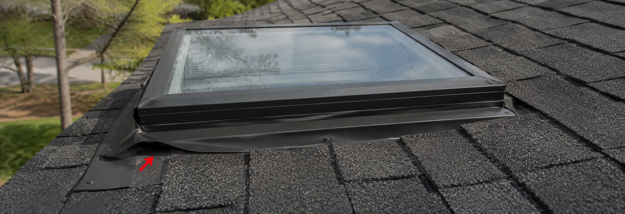 Exterior view of a residential roof skylight showing subtle lifted flashing at the upper corner